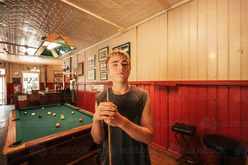 Teenage male playing 8 ball pool on billiard table in Australian pub - Australian Stock Image