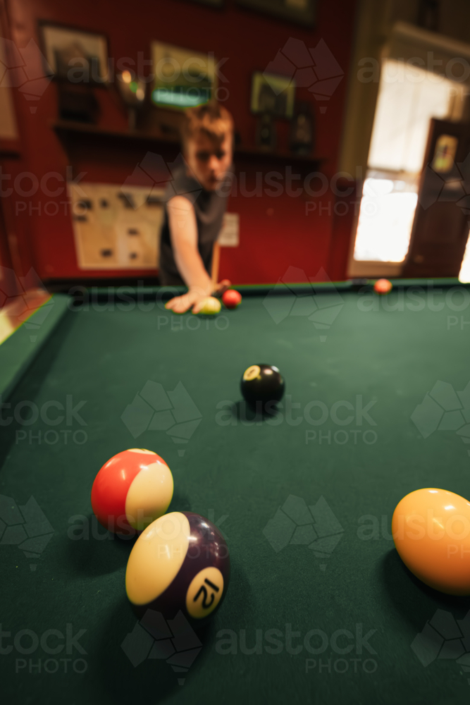 Teenage male playing 8 ball pool on billiard table in Australian pub - Australian Stock Image