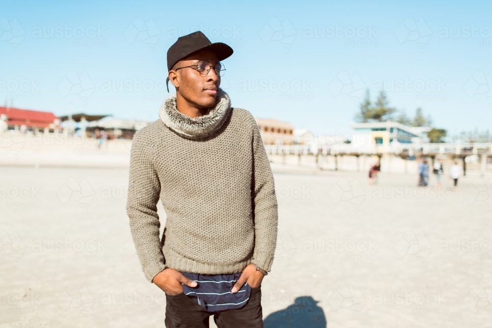 Teenage man standing on a sandy beach posing - Australian Stock Image