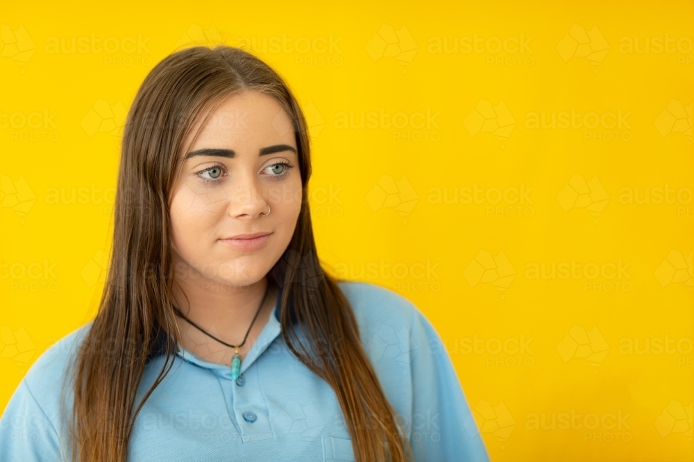 teenage schoolgirl with long hair offset on yellow background - Australian Stock Image