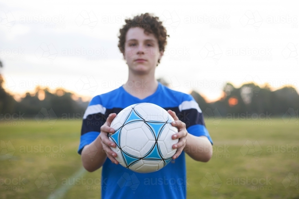 Teenage soccer player on a soccer pitch with ball - Australian Stock Image