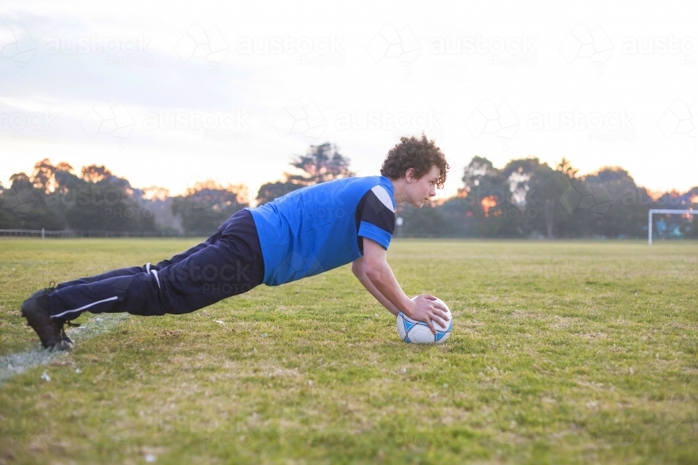 Teenage soccer player on a soccer pitch with ball - Australian Stock Image