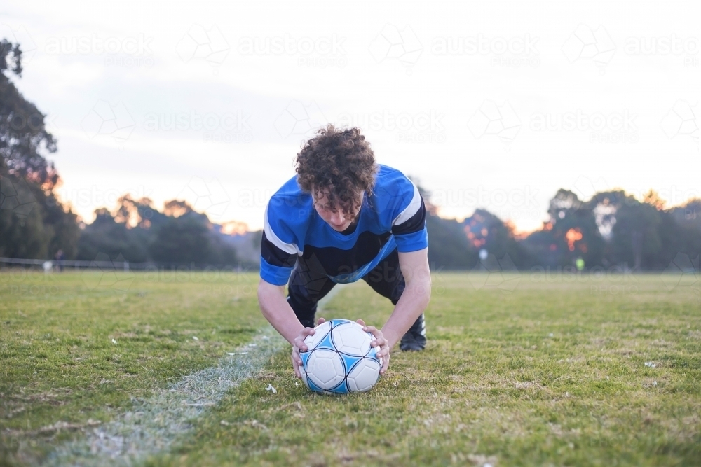 Teenage soccer player on a soccer pitch with ball - Australian Stock Image