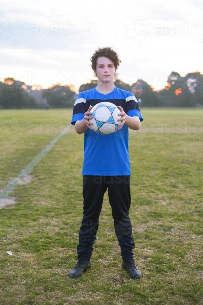 Teenage soccer player on a soccer pitch with ball. - Australian Stock Image