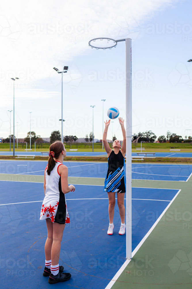 Teenaged aboriginal netball player shooting a goal on the court - Australian Stock Image