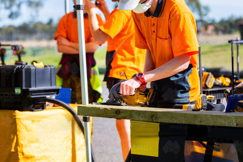 Image of Teenaged trade apprentice using circular saw tool to cut wood ...