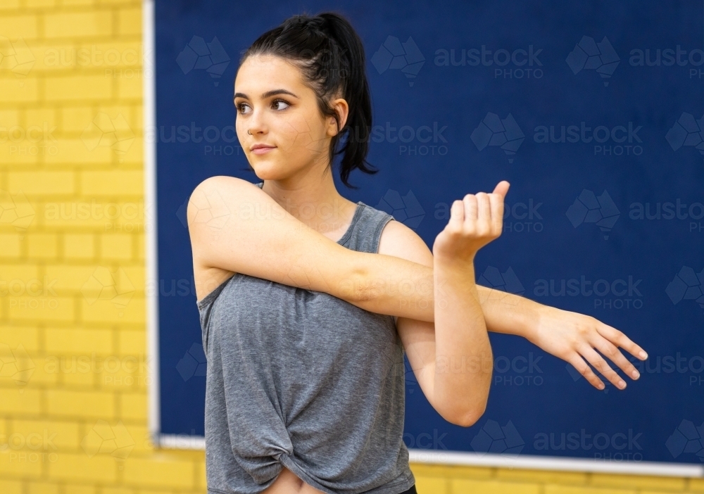teenager doing arm stretching exercises - Australian Stock Image