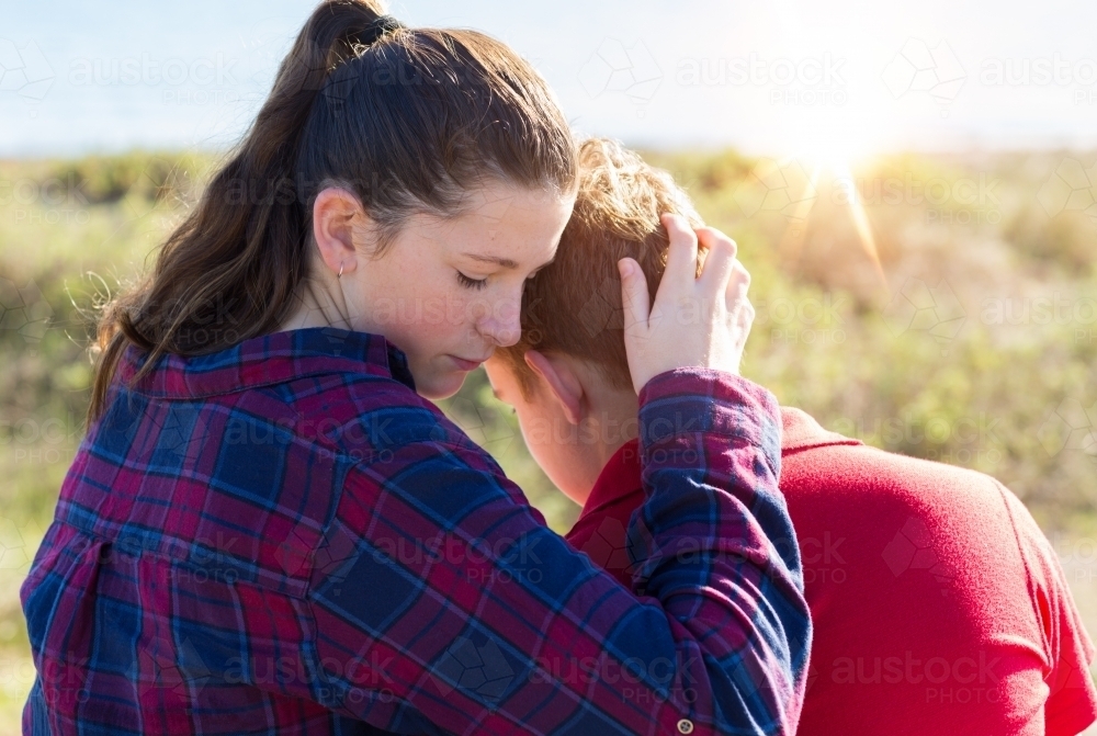 Image of Teenager girl holding boy close Austockphoto