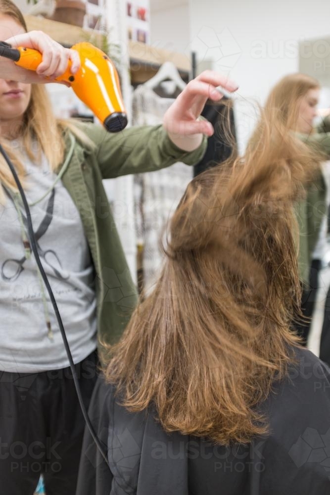 Teenager having hair blow dried at the hairdresser - Australian Stock Image