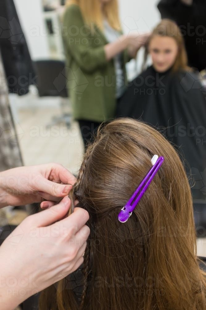 Teenager having hair braided at the hairdresser - Australian Stock Image
