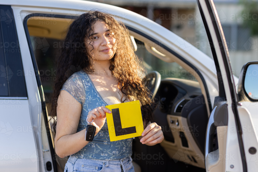 teenager holding L Plate and key fob in front of vehicle - Australian Stock Image