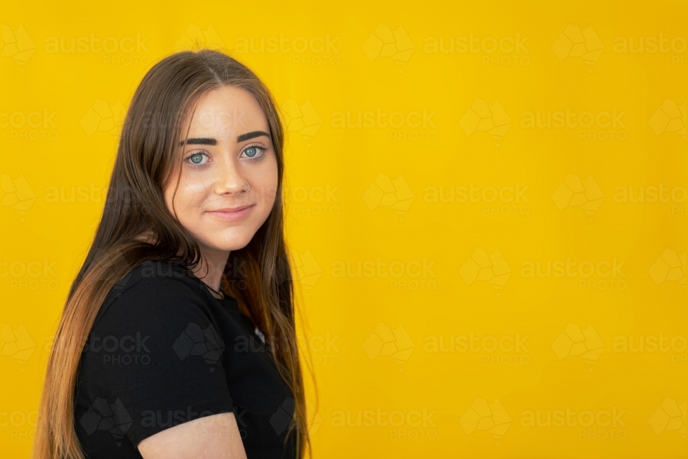 teenager in black tee shirt in front of yellow background - Australian Stock Image