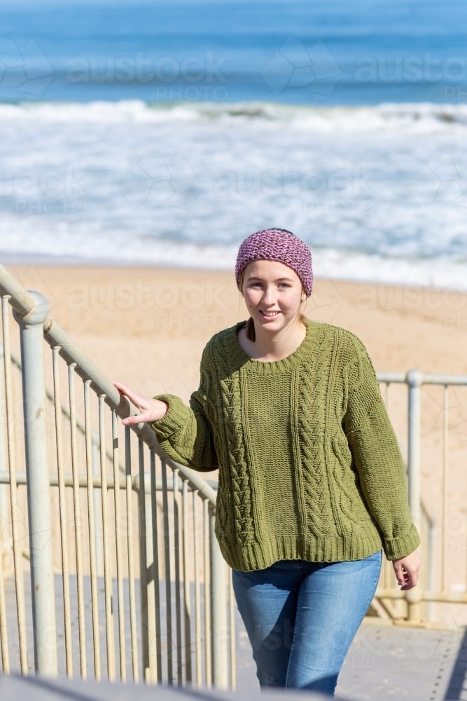 Teenager in warm clothes on steps to beach - Australian Stock Image