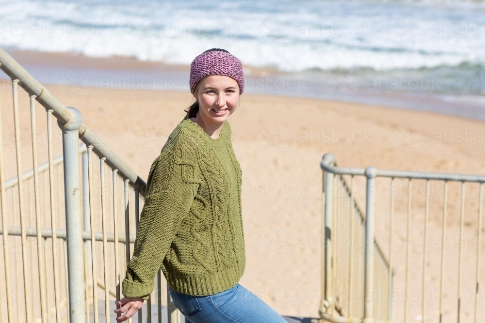 Teenager in warm clothes on steps to beach - Australian Stock Image