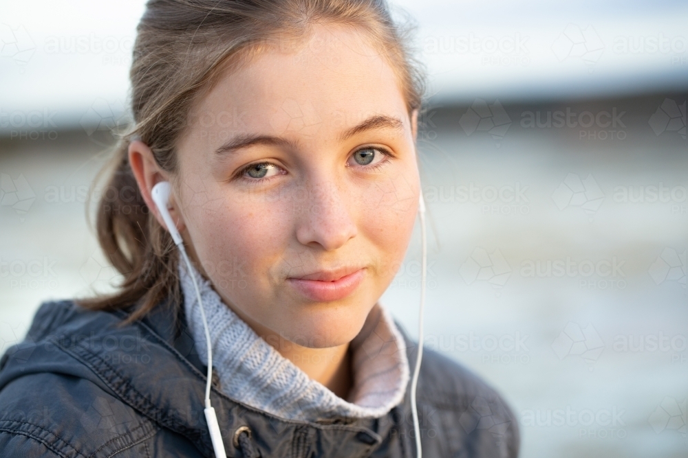 Teenager looking at camera with music in ears - Australian Stock Image