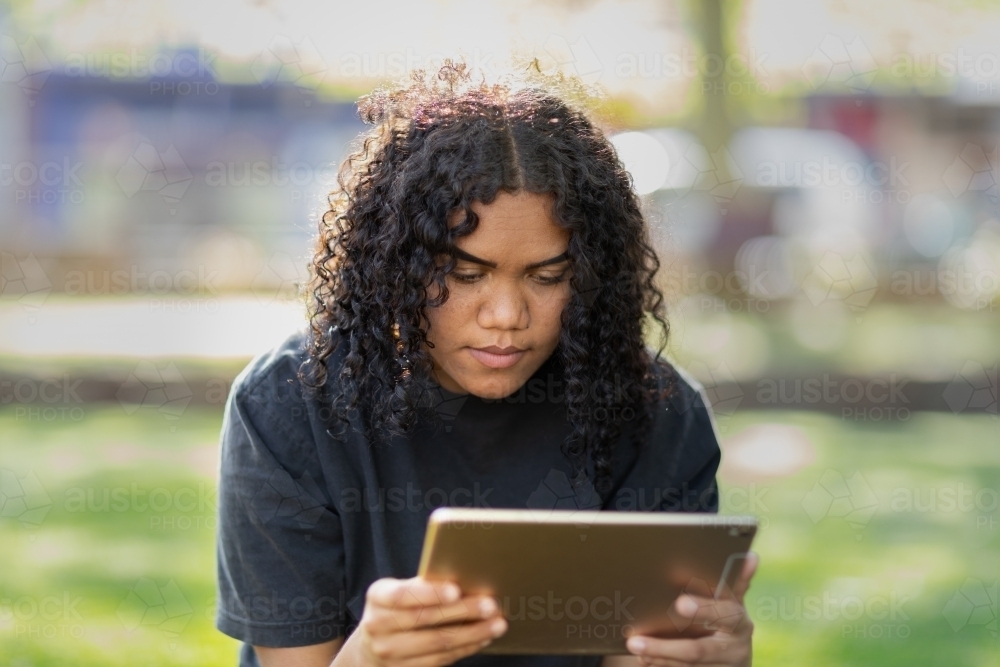 teenager looking at digital tablet outdoors in garden - Australian Stock Image