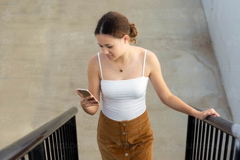 Teenager looking at phone on staircase - Australian Stock Image