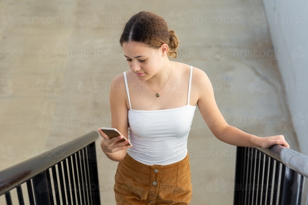 Teenager looking at phone on staircase - Australian Stock Image
