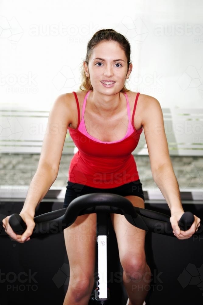 teenager on a stationary bike at the gym - Australian Stock Image
