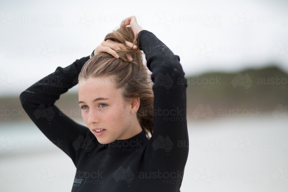 Teenager pulling hair back into ponytail - Australian Stock Image