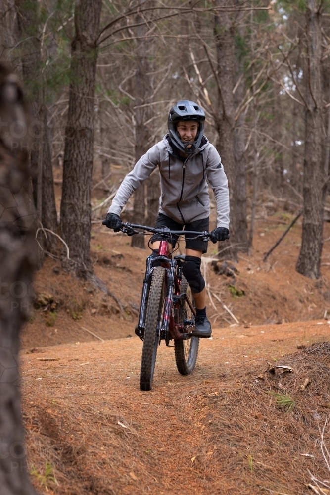 teenager riding mountain bike through the pine forest - Australian Stock Image
