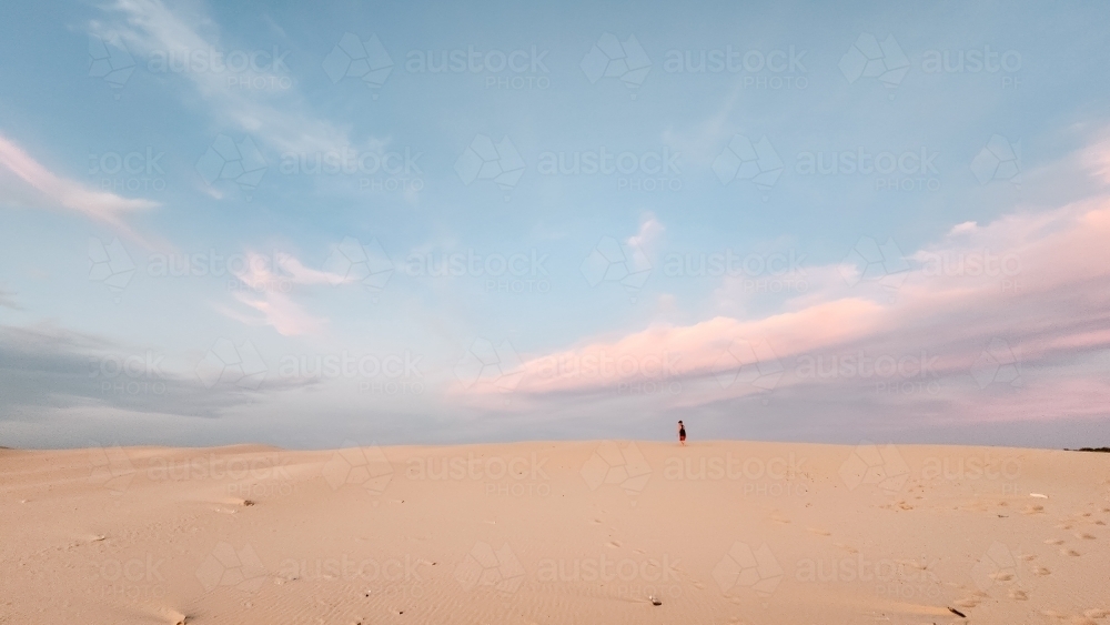 Teenager walking on the sand dunes at Birubi Beach at sunset - Australian Stock Image