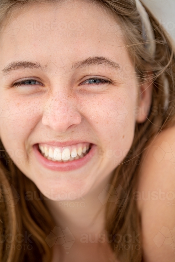 Teenager with cheesy grin and grains of sand on her face - Australian Stock Image