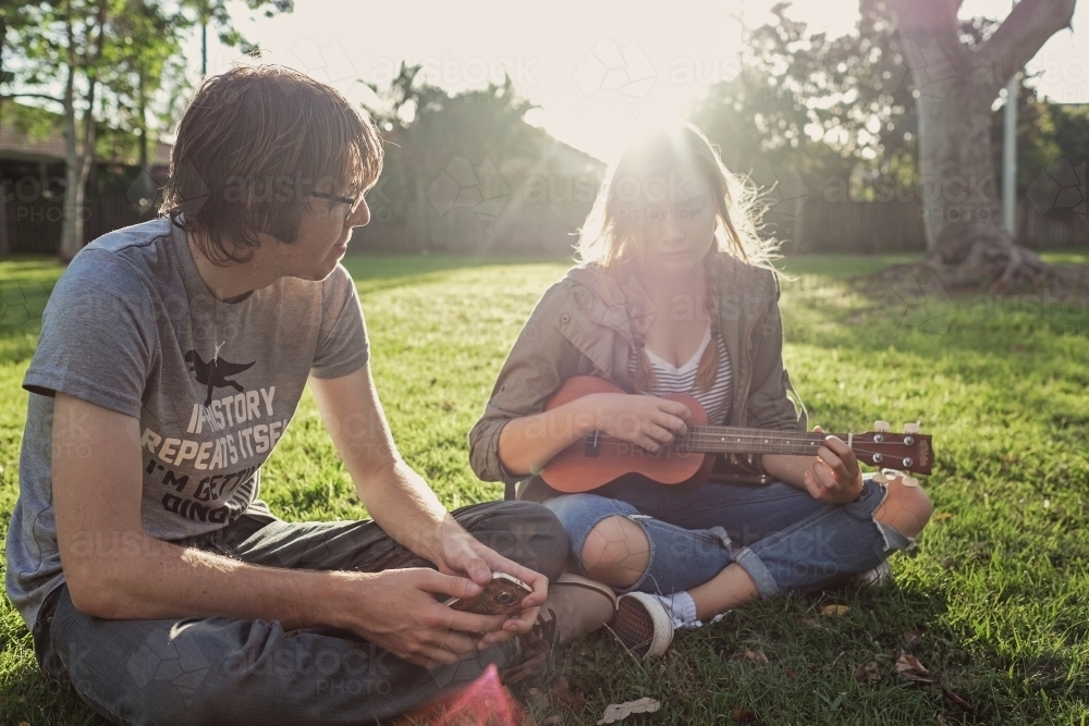 Teenagers playing ukulele in the park - Australian Stock Image