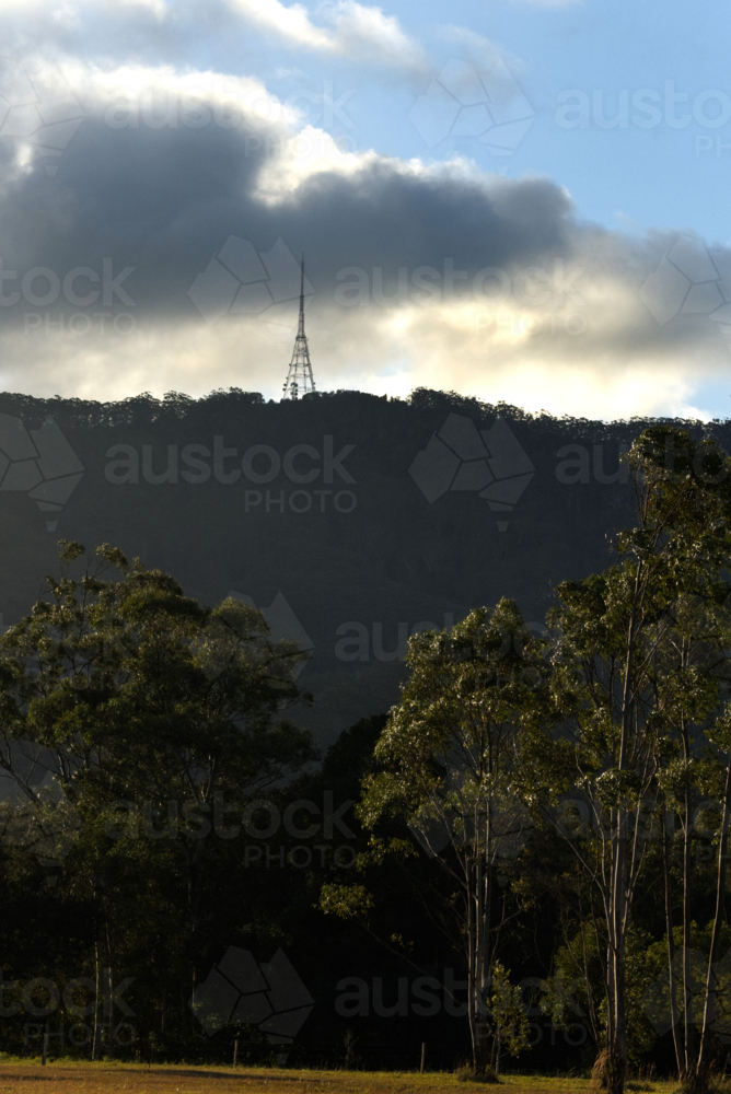 telecommunications tower on a hill in the distance, trees, clouds, blue sky - Australian Stock Image