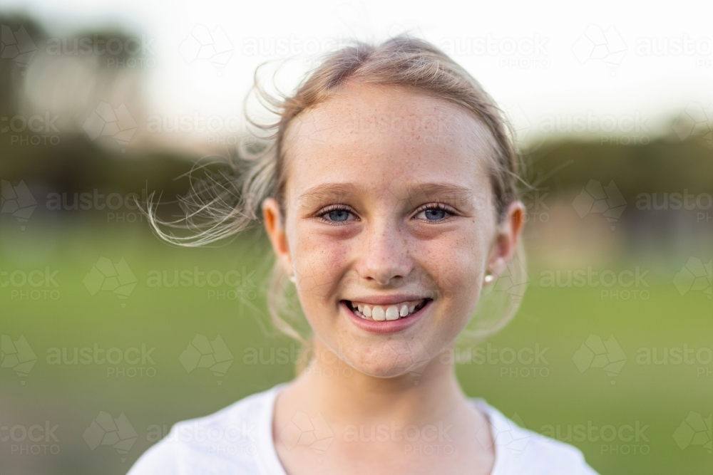 ten year old child with blonde hair and blue eyes smiling with blurry background - Australian Stock Image