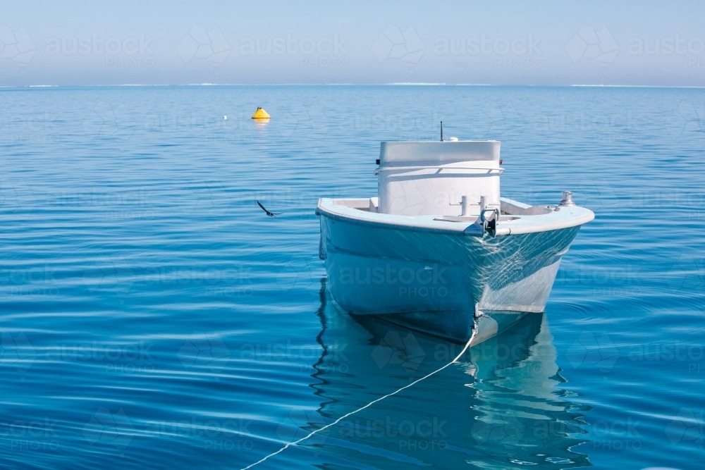 Tender jet boat on its mooring on a calm blue ocean - Australian Stock Image