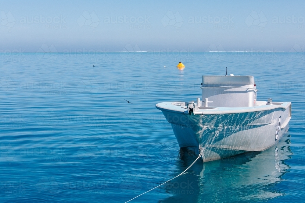 Tender jet boat on its mooring on a calm blue ocean - Australian Stock Image