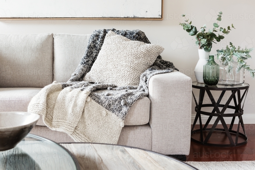 Textured layers interior styling of cushion sofa and throw in neutral colors - Australian Stock Image