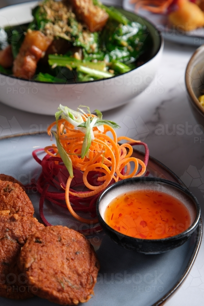Thai fish cakes served on a plate with salad crunch and chili sauce on the side. - Australian Stock Image