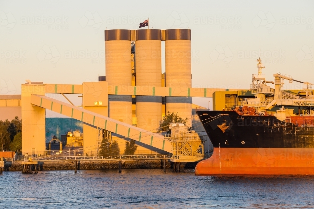 The bow of a ship docked near tall grain silos at the Port of Brisbane - Australian Stock Image