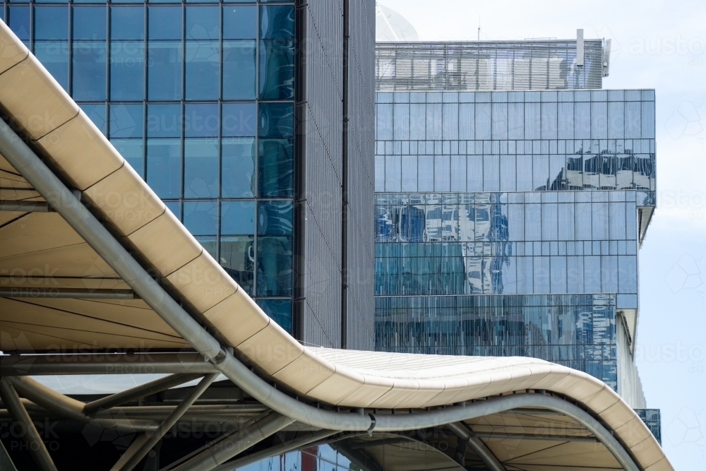 The curved edge off a buildings roof in front of high rise office blocks - Australian Stock Image
