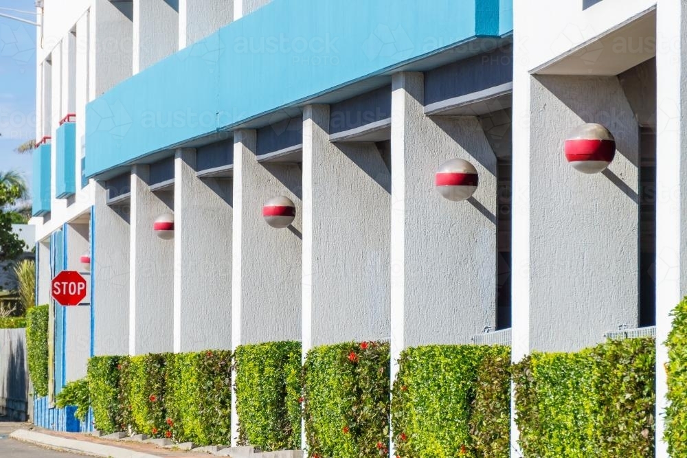 The facade of a building with a line of pillars and hedges - Australian Stock Image
