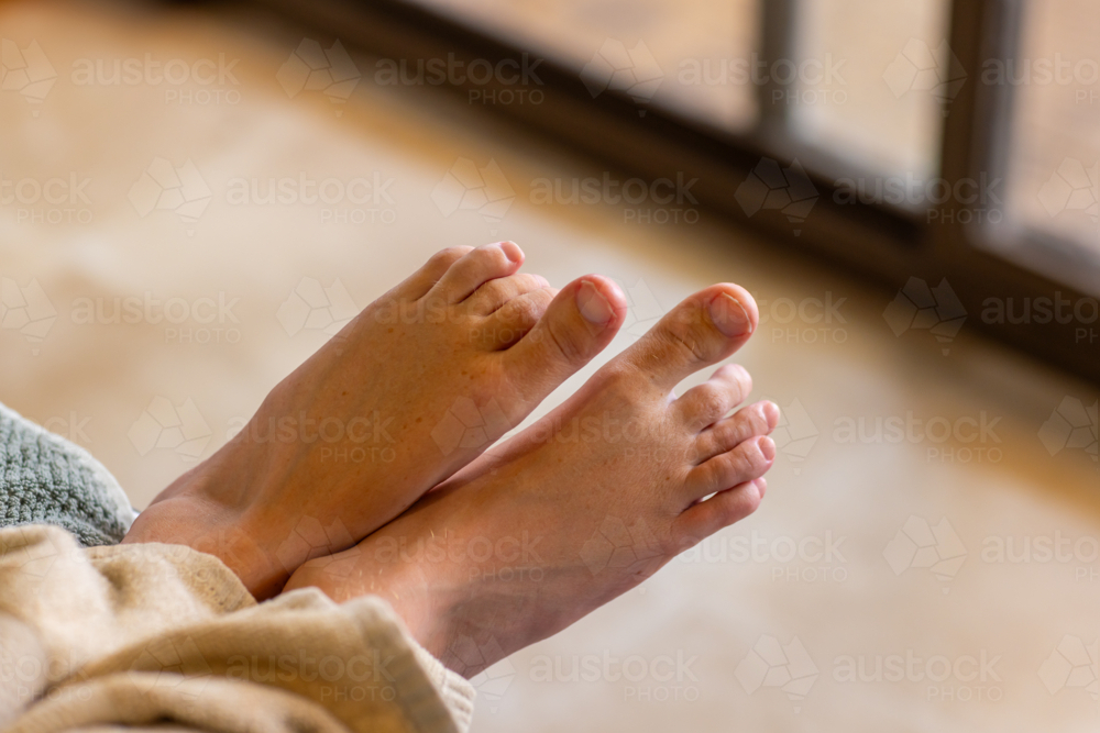 the feet of a young man with cerebral palsy poking out from under a blanket - Australian Stock Image
