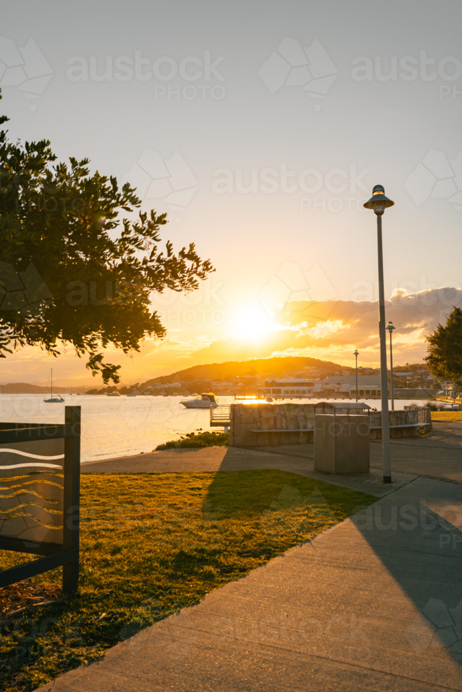 The footpath through Belmont Lions park on the shoreline of Lake Macquarie at sunset - Australian Stock Image