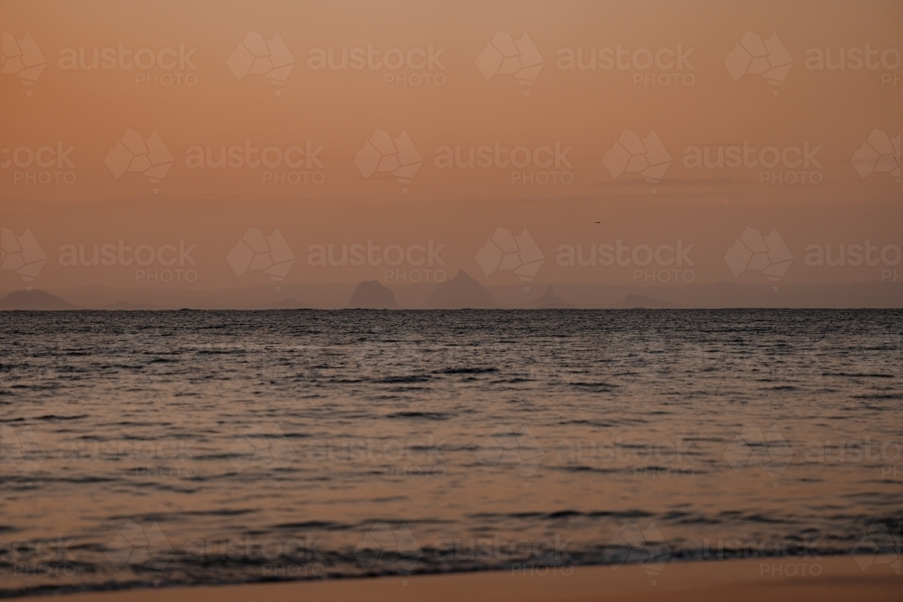 The Glasshouse Mountains visible from Moreton Island at sunset - Australian Stock Image