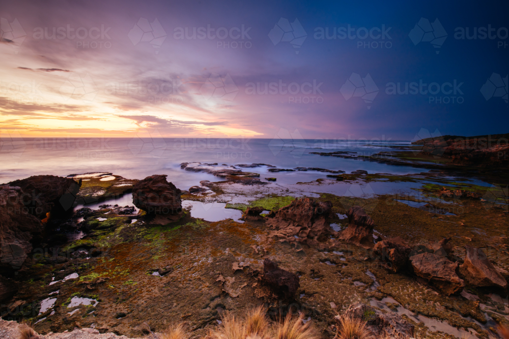The idyllic Pearses Beach and headland around Pirates Bay Cove on a hot summer's evening. - Australian Stock Image
