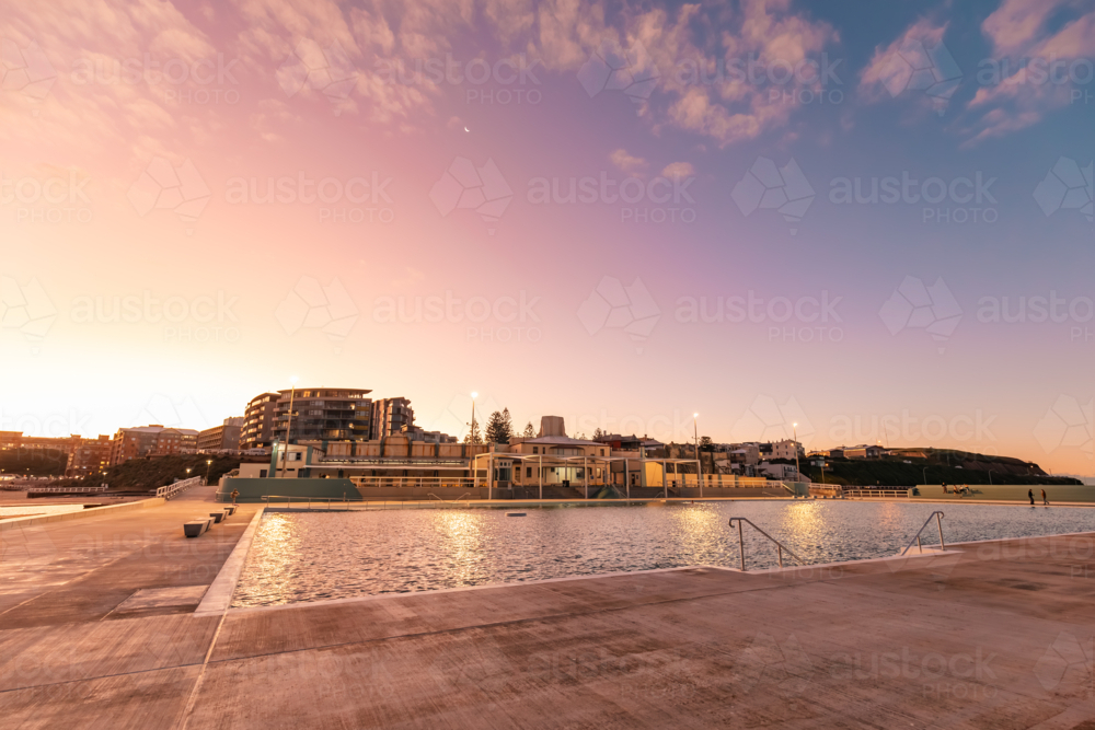 The Newcastle Ocean Baths at dusk with pink and purple fairy floss sky - Australian Stock Image