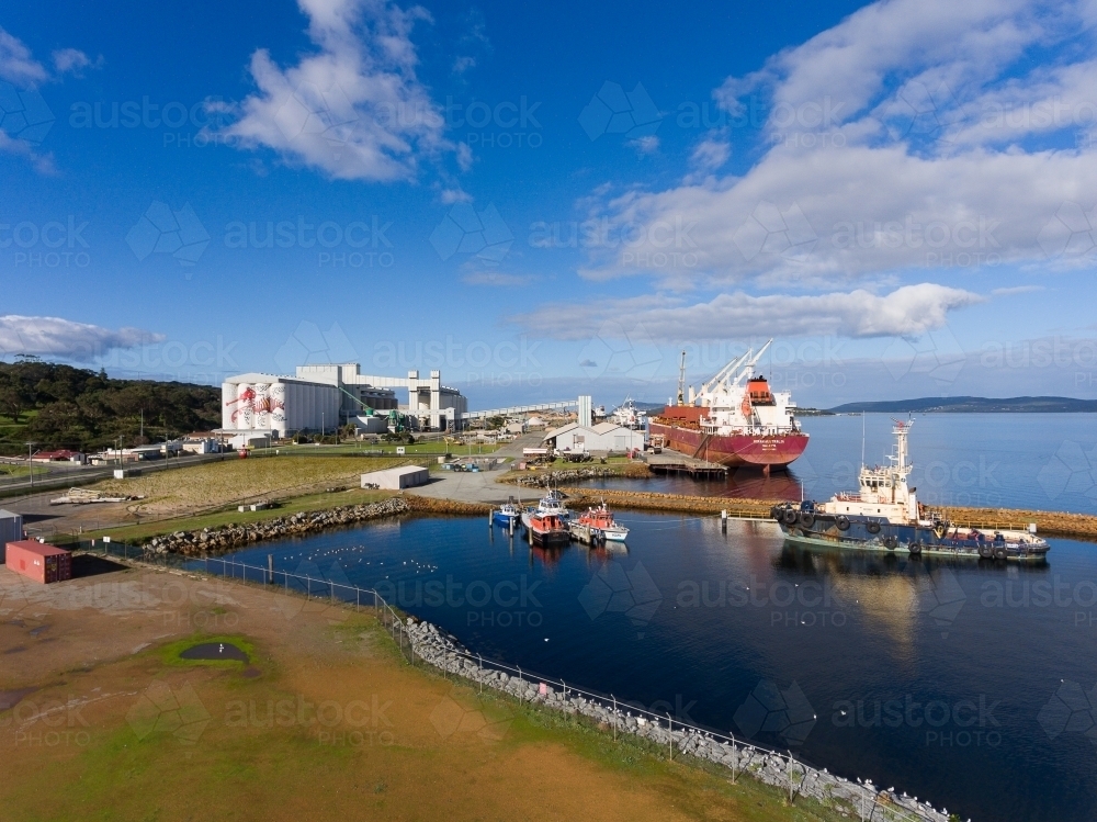 the port at Albany with silos, ship docked and tugboat in foreground - Australian Stock Image