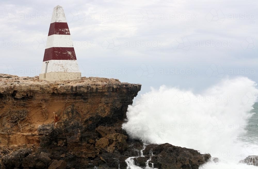 The red and white obelisk on rocky cliff by the sea - Australian Stock Image