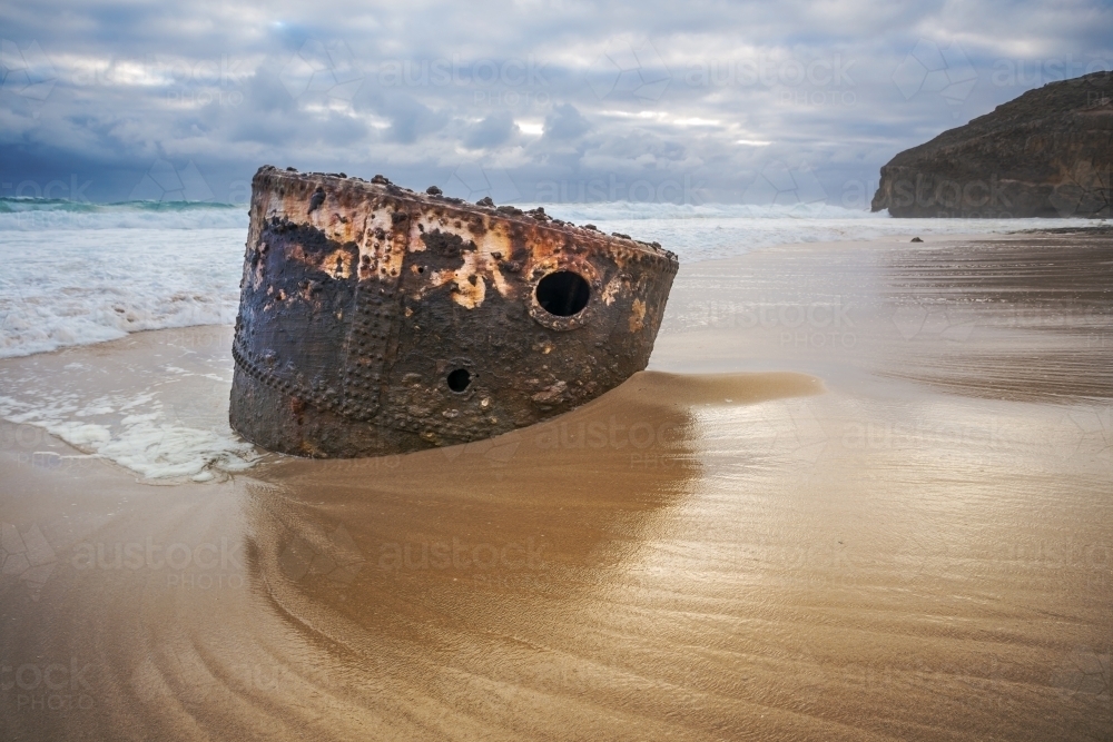 The rusty boiler of a shipwreck sticking out of the sand on an isolated beach - Australian Stock Image