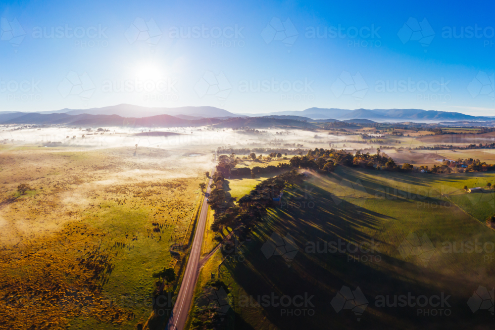 The sun rises through fog on a cold autumn morning near Yarra Glen in the Yarra Valley, Victoria - Australian Stock Image