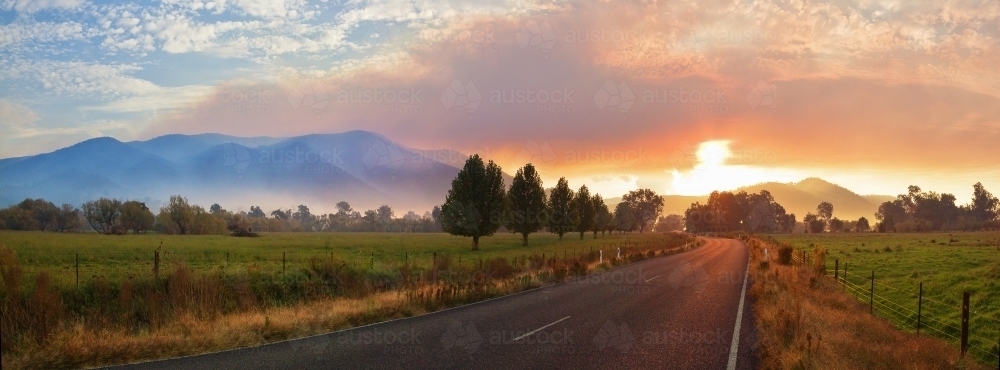 The Sun sinking into a band of smoke haze around a mountain range - Australian Stock Image