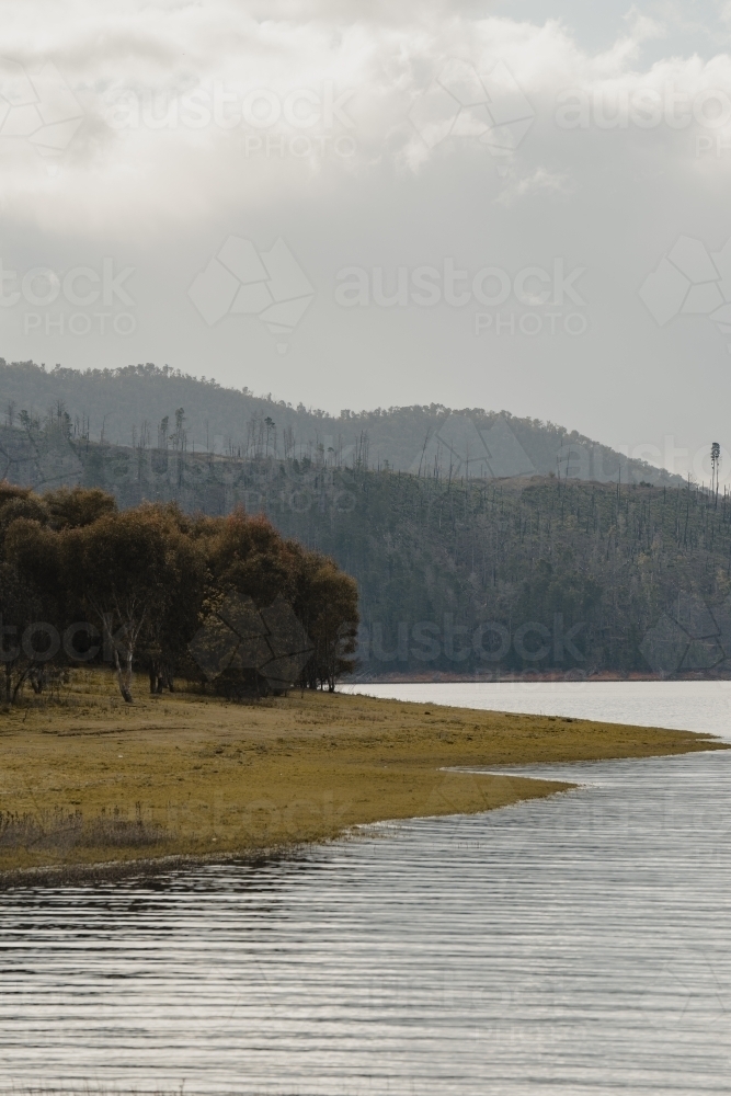 The water's edge with mountains in the background at Blowering Reservoir - Australian Stock Image