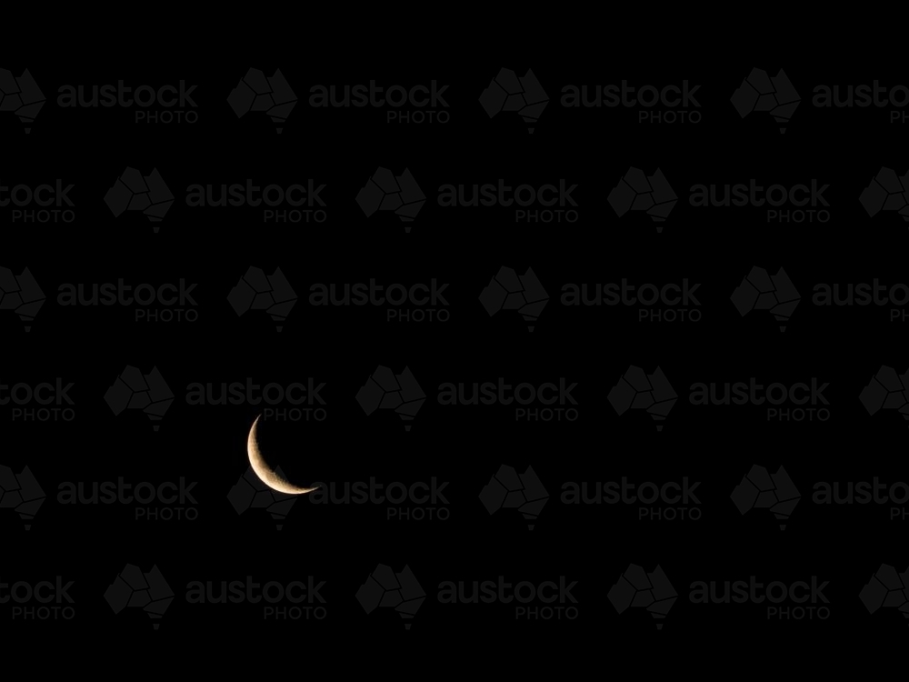 Thin crescent moon in a very dark sky in bottom left corner - Australian Stock Image