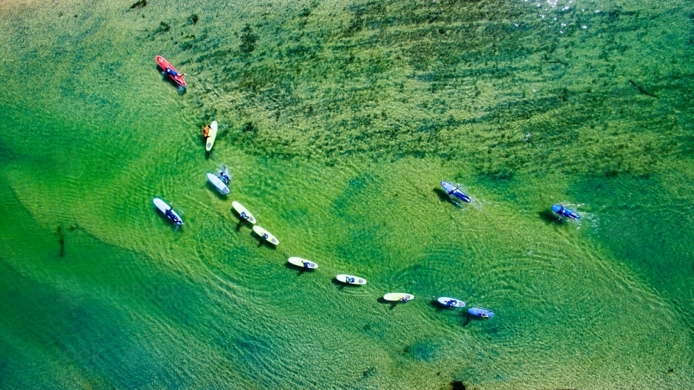 Thirteen paddle boarders SUP on Cudgera Creek at Hastings Point - Australian Stock Image